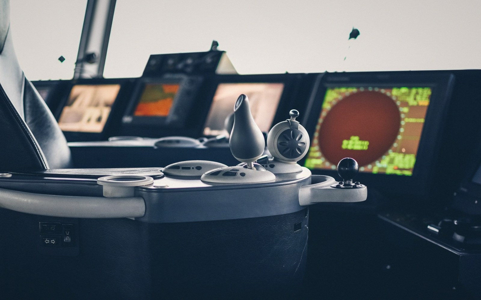 Ship's bridge control console with radar display and navigation screens glowing in the dark