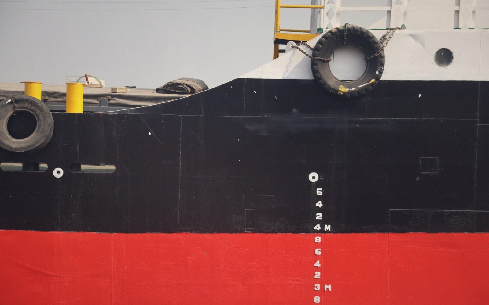 Ship's hull showing draft marks and tire fenders mounted near the bow