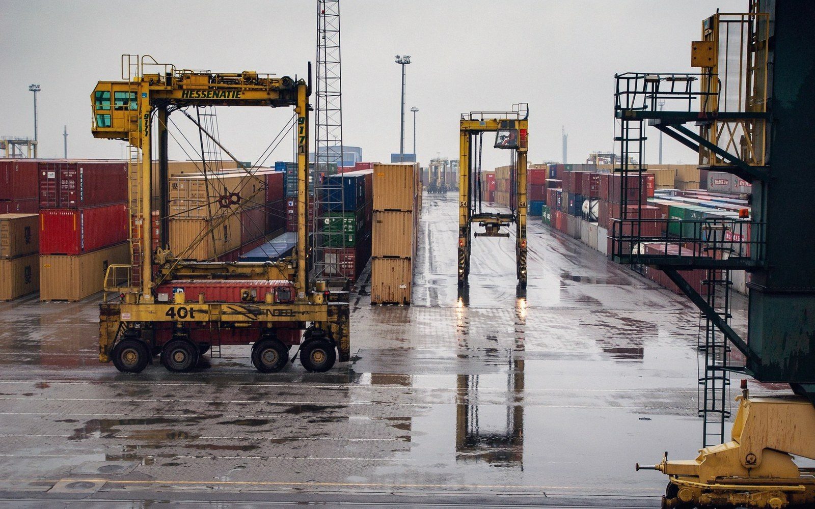 Straddle carriers move shipping containers across a wet dockside terminal
