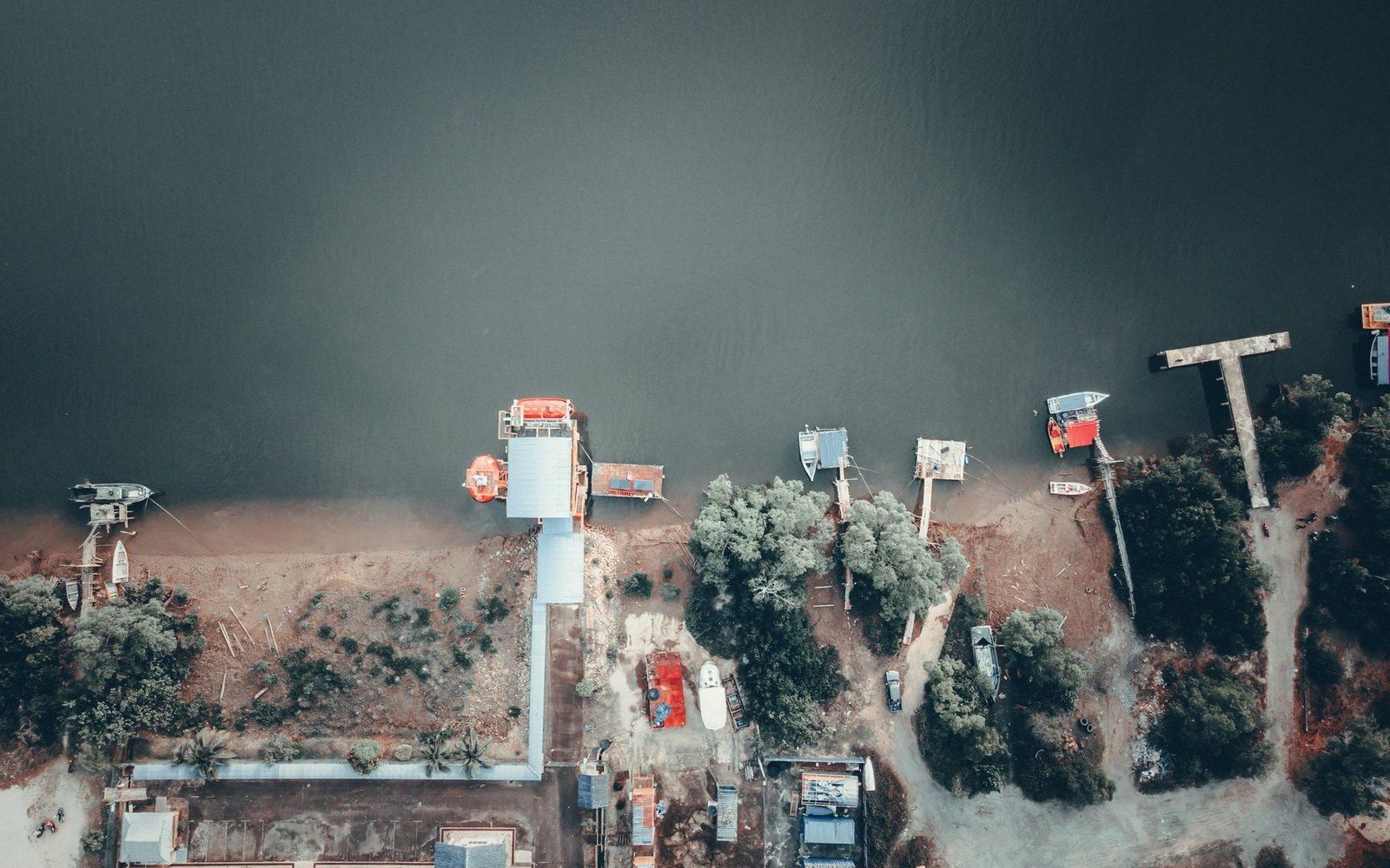 Aerial view of small boats moored along a riverbank with scattered dockside buildings
